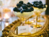 a wedding dessert setting with a refined gold tray, black and gold berry desserts