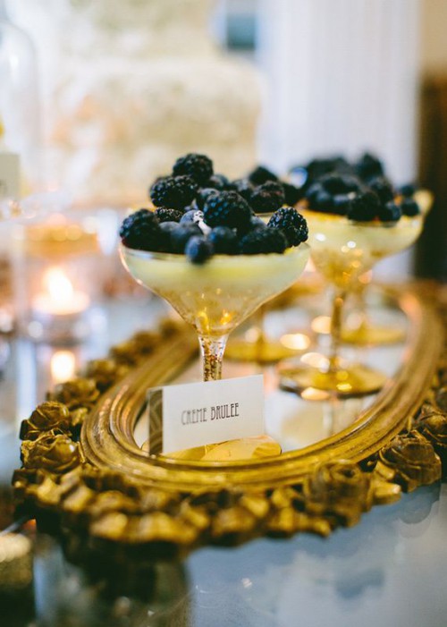 a wedding dessert setting with a refined gold tray, black and gold berry desserts