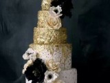 a white wedding cake decorated with gold touches with black and white blooms