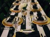 a chic tablescape with a striped tablecloth, black chargers and cutlery, striped menus and black bows