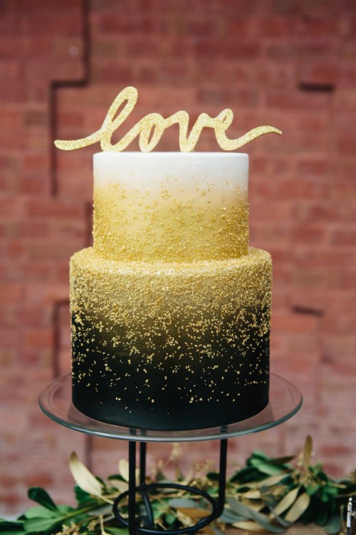 a black and white wedding cake decorated with gold glitter and with a gold glitter topper