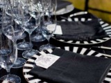 a Halloween wedding tablescape with a black tablecloth, striped plates and clear glasses