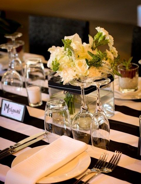 a quirky tablescape with a striped black and white tablecloth, neutrals blooms, porcelain and napkins plus silver