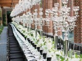 a modern wedding tablescape with white blooms, tall crystal candle holders and matching chandeliers and black glasses and napkin rings