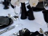 an exquisite tablescape with white orchids in black vases, black plates and chargers, black napkins and favors boxes
