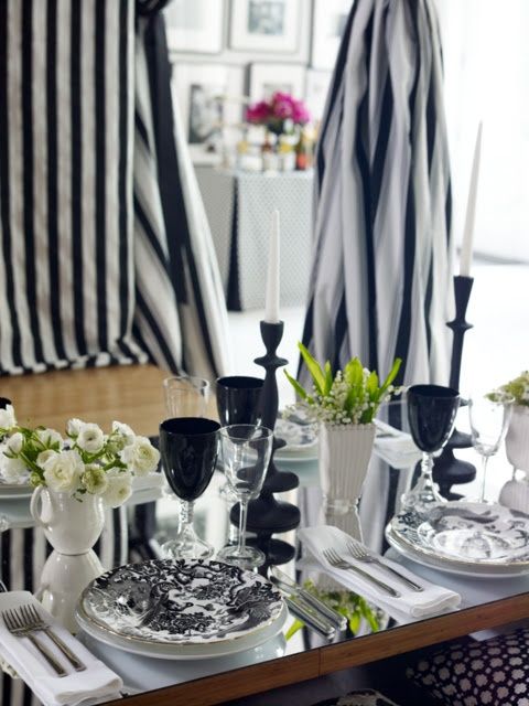 a stylish black and white wedding tablescape with printed plates, black glasses and candleholders and neutral blooms