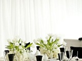white tablecloths, clear and black glasses, white porcelain and white flowers for centerpieces