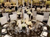 a black and white tablescape with candles, white blooms, white plates and black napkins