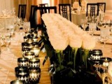 a gorgeous refined black and white tablescape with a large and long white rose centerpiece in a black box, black geometric candle holders and white porcelain