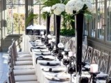 an exquisite black and white tablescape with black plates and glasses, tall black vases and white blooms, white candles in black candle holders