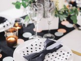a playful black and white tablescape with a polka dot runner and plate, a black bow napkin and some neutral blooms
