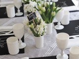 black chalkboard placemats, neutral blooms, white glasses and candle holders for a casual wedding tablescape