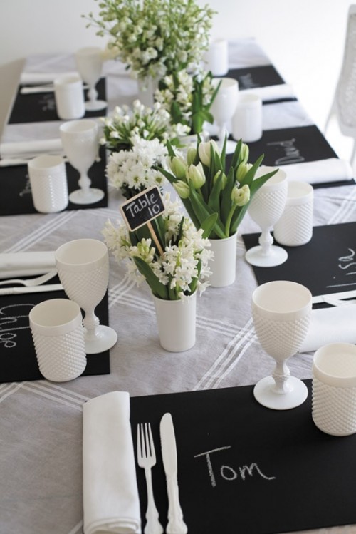 black chalkboard placemats, neutral blooms, white glasses and candle holders for a casual wedding tablescape