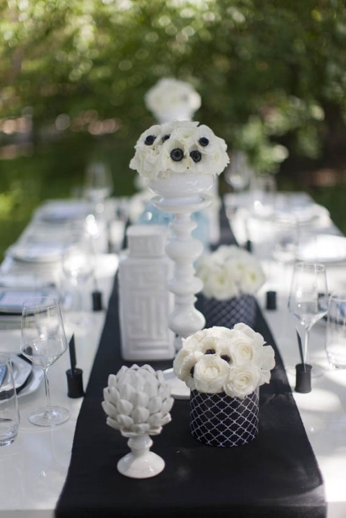 a black table runner, vase covers and card holders add a dramatic touch to this pure white table setting