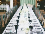 a white tablecloth, black lace placemats, black glasses, white bloom centerpieces