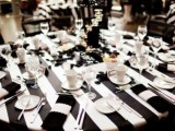 a striped black and white tablecloths, black napkins, white porcelain, elegant candleholders