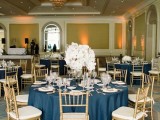 a navy, white and gold tablescape with a lush floral centerpiece and gold candles
