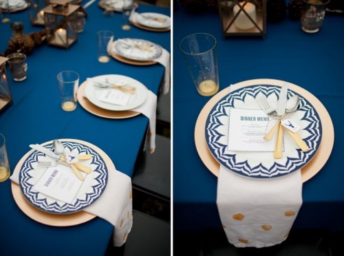 a navy, gold and white wedding tablescape with candle lanterns and pinecones