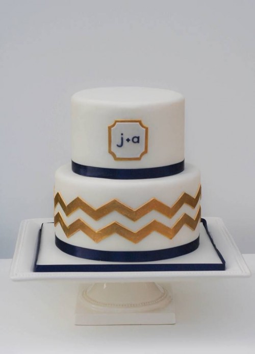 a chic white, navy and gold wedding cake with a timeless chevron pattern