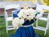 a navy cocktail table with white lush blooms and gold buntings and accessories