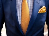 a navy suit, a printed blue shirt, a gold tie and handkerchief
