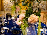 a chic navy tablescape with gold touches, candles and lush floral centerpieces