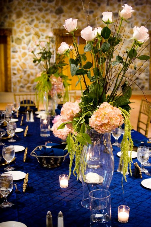 a chic navy tablescape with gold touches, candles and lush floral centerpieces