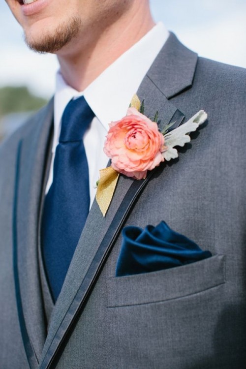 a grey suit with navy accessories and a single coral bloom boutonniere
