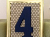 a navy table number in a gold frame with a polka dot backdrop
