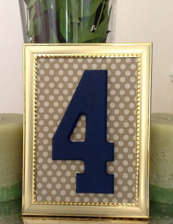 A navy table number in a gold frame with a polka dot backdrop