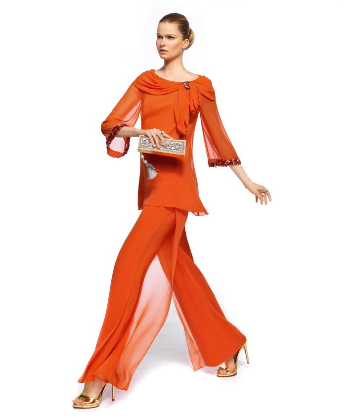 an orange suit   a top with long sleeves and a draped neckline and flowy pants plus an elegant clutch and gold shoes to make a statement with color