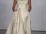 a silk A-line tea length wedding dress with a pleated skirt and pockets, with a deep V-neckline that is embellished, a fabric bloom as a headpiece and silver shoes