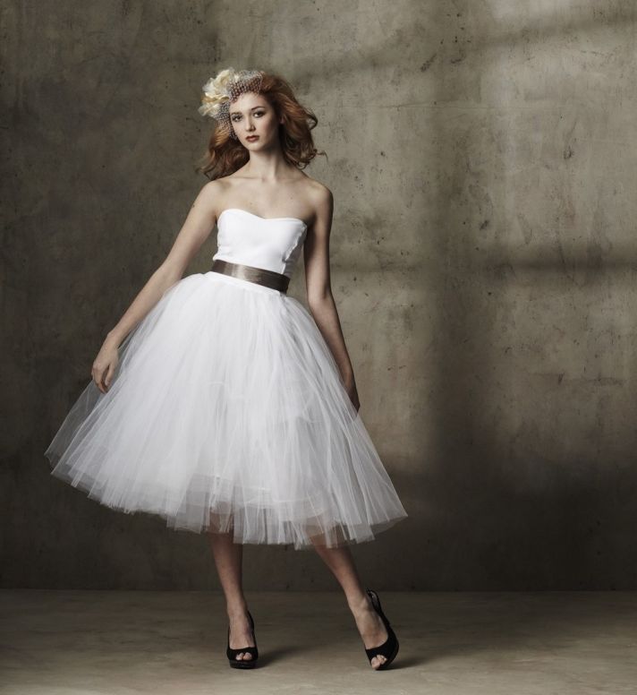 A strapless a line wedding dress with a plain bodice and a tulle skirt, a sash and black shoes for a modern take on a traditional look