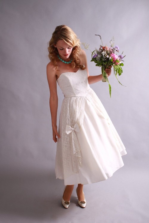 a strapless A-line tea length wedding dress with a lace bodice and a plain skirt accented with curtains and bows plus vintage shoes
