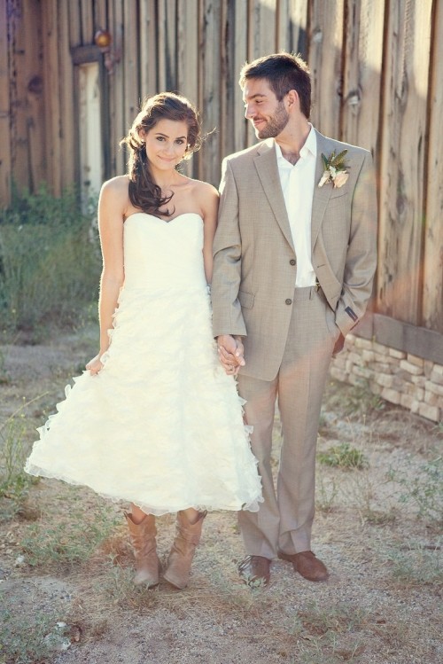 a strapless A-line tea length wedding dress with a plain bodice and lace applique tiered skirt and cowboy boots for a lovely rustic-inspired look