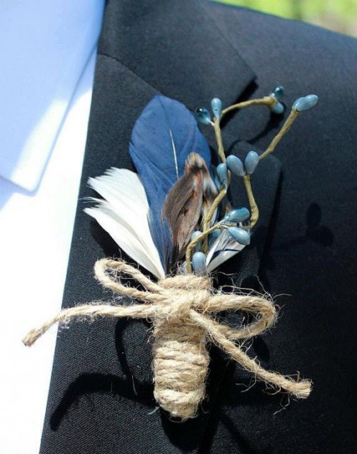 a vintage boho wedding boutonniere of feathers, berries and a twine wrap is a stylish idea for accenting a boho groom's look