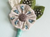 a whimsical vintage wedding boutonniere of a fabric piece with a button, fabric leaves and lace can be DIYed to personalize it
