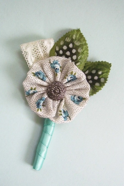 a whimsical vintage wedding boutonniere of a fabric piece with a button, fabric leaves and lace can be DIYed to personalize it