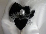 a vintage wedding boutonniere of black petals, a pearl and white feathers is an elegant and refined touch to the groom’s look