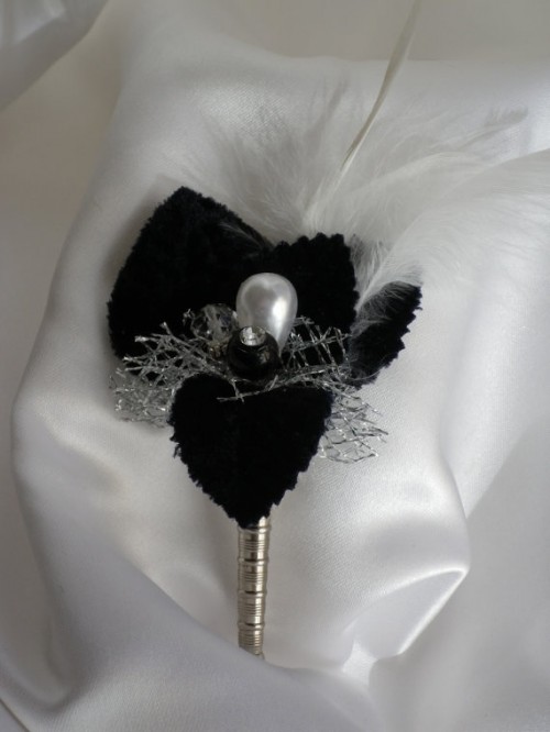 a vintage wedding boutonniere of black petals, a pearl and white feathers is an elegant and refined touch to the groom's look