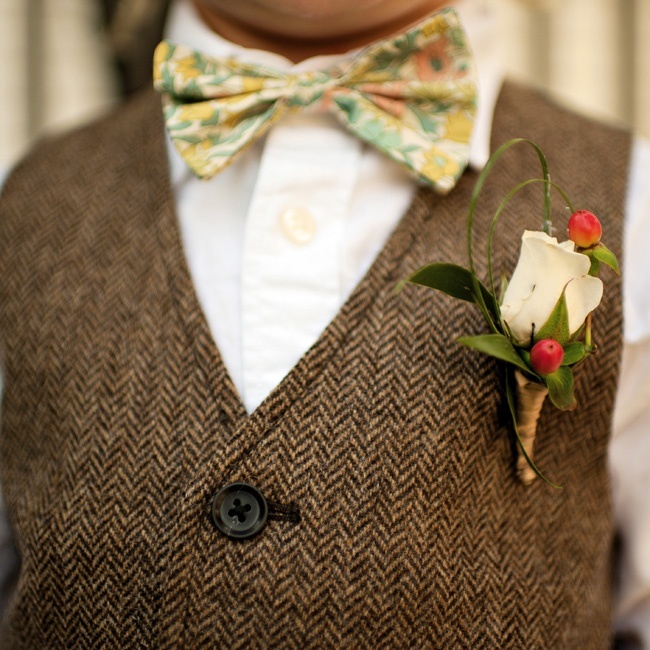 a vintage wedding boutonniere of a white rose, greenery and berries plus a wrap is a stylish solution for many groom's looks