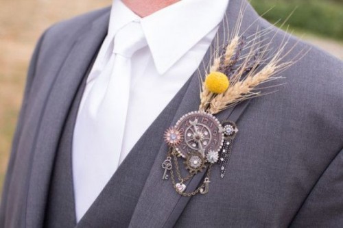 a catchy vintage wedding boutonniere of a vintage clock face, wheels, a vintage key, some dried blooms and grass is amazing