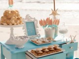 a blue dessert table with various sweets and cakes styled for a beach bridal shower is perfect for your party