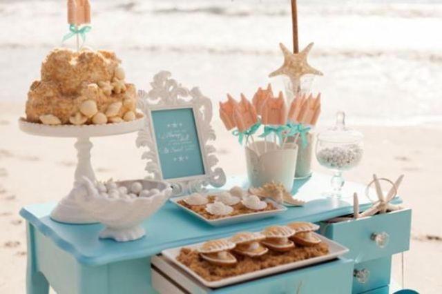 A blue dessert table with various sweets and cakes styled for a beach bridal shower is perfect for your party