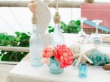 a chic beach bridal shower table done with turquoise glasses, seashells, starfish, bright blooms, a white sea horse decoration