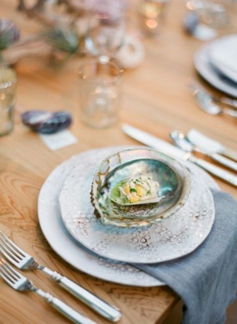 a beach bridal shower tablescape with printed plates, blue napkins, a seashell as an appetizer plate