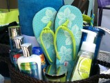 a beach bridal shower welcoming basket with flipflops, a towel, sunscreen, sea salt hair spray and other stuff