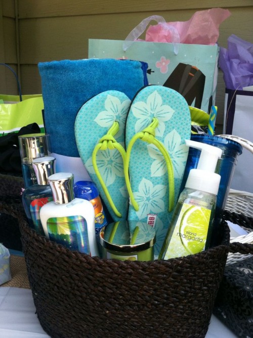 a beach bridal shower welcoming basket with flipflops, a towel, sunscreen, sea salt hair spray and other stuff