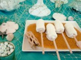 a beach bridal shower dessert table with marshmallow pops, candies, net and seashells