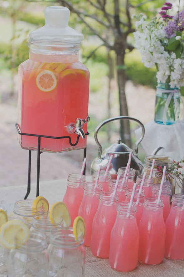 Pink lemonade in a tank and bottles with fresh citrus is an ideal drink for a summer bridal shower